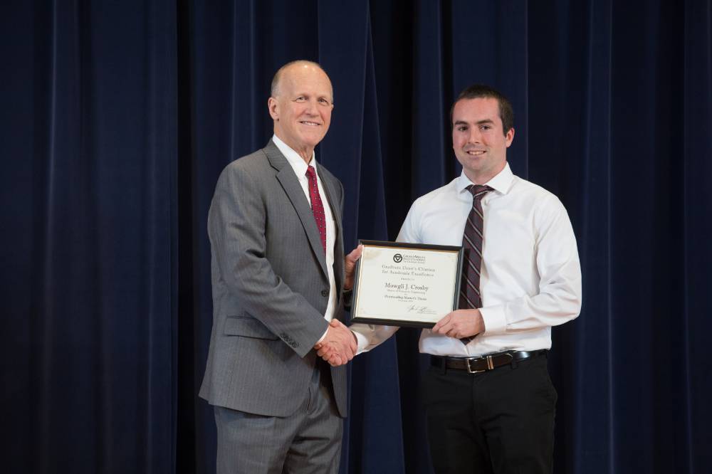Dean Potteiger posing for a photo with an award and the graduate student who has received it